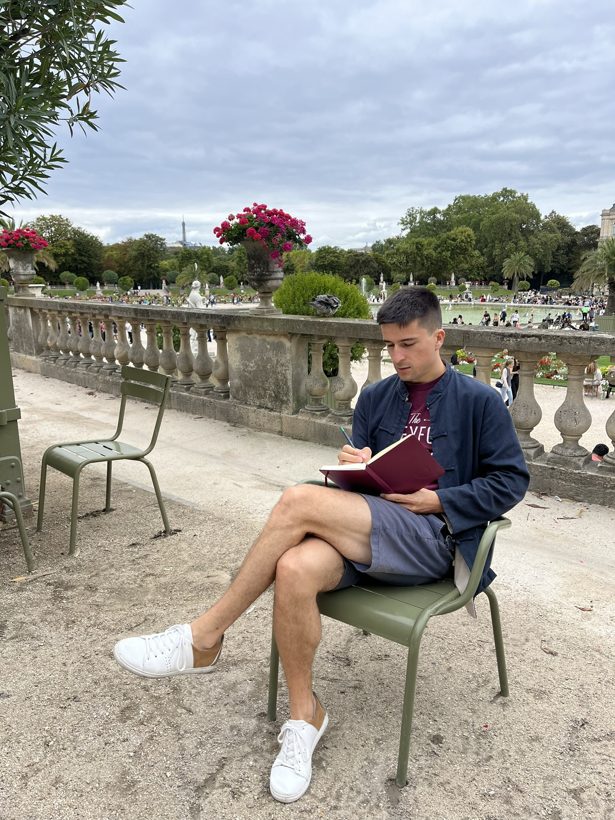 Jonas writing in a notebook in a Paris park